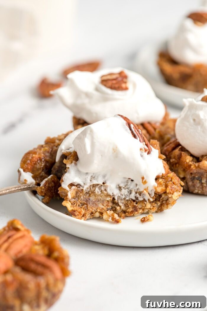 Quick and Easy No-Bake Pecan Tartlets 9 Close up of a pecan pie tart topped with whipped cream on a small plate.