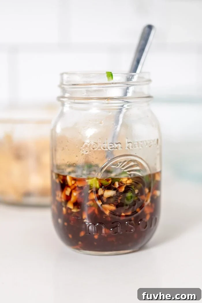 A hand whisking or shaking all the dressing ingredients together in a container to combine them thoroughly.