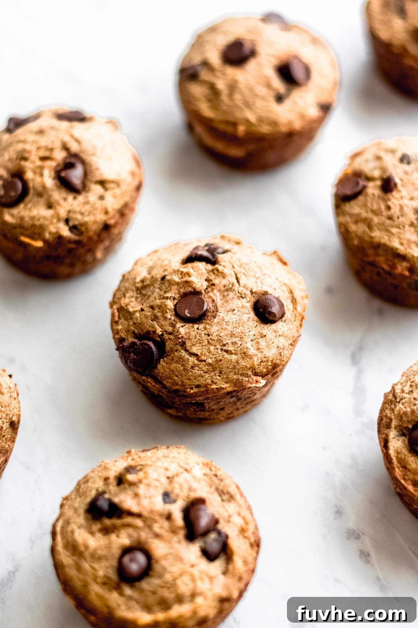 Decadent Vegan Chocolate Chip Banana Muffins 2 Beautifully arranged vegan chocolate chip banana muffins on a pristine marble surface, inviting you to take a bite.