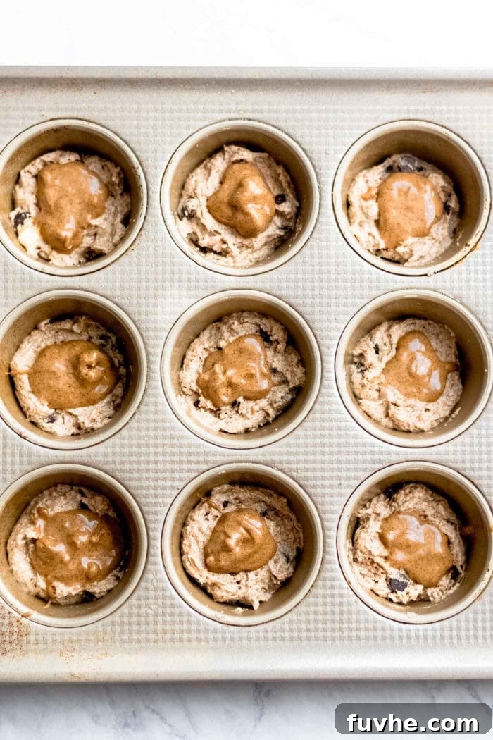 Decadent Vegan Chocolate Chip Banana Muffins 5 Raw muffin dough for vegan chocolate chip banana muffins, revealing a spoonful of almond butter nestled in the center before baking.