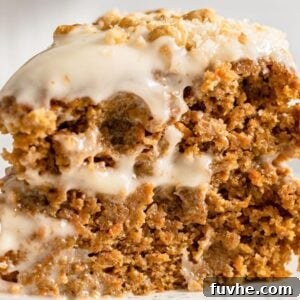 A beautifully presented slice of double layered vegan carrot cake, topped with creamy frosting and garnished with walnuts, ready to be served.