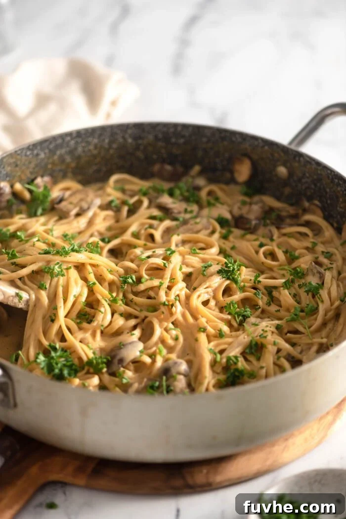 Plant-Based Carbonara 8 Creamy vegan carbonara pasta with fresh parsley in a large skillet sitting on a cutting board.