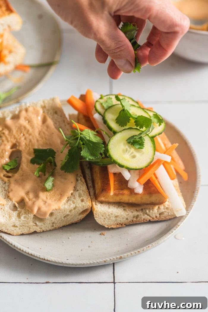 Ultimate Vegan Tofu Banh Mi 7 Hand sprinkled cilantro over a tofu banh mi sandwich.