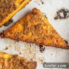 A perfectly baked triangle of golden brown garlic herbed marinated tempeh, presented on a round plate, ready to be enjoyed.