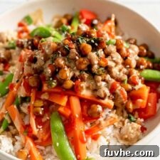 Chickpeas in teriyaki sauce served over stir fried vegetables and rice and topped with scallions and sesame seeds.