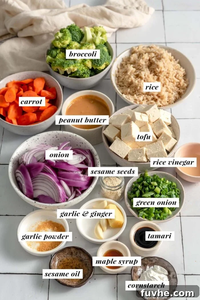 All ingredients needed for making a vegan tofu peanut bowl with vegetables and rice. Each ingredient is labelled with text.