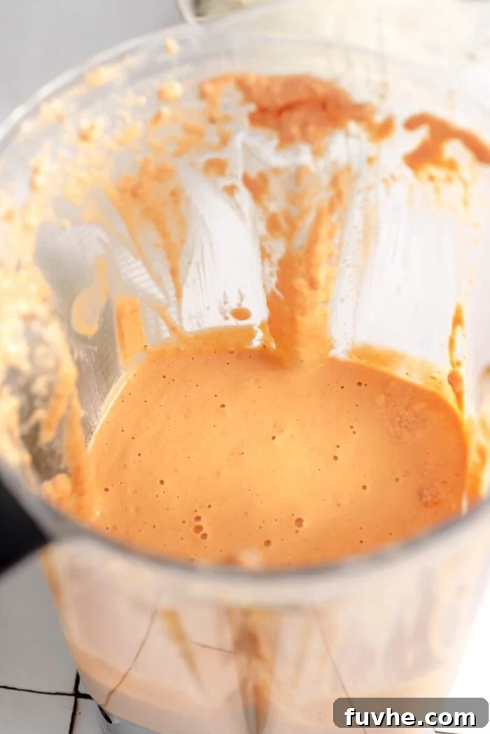 A high-speed blender container filled with the creamy sun-dried tomato sauce, showing its vibrant color and smooth consistency.