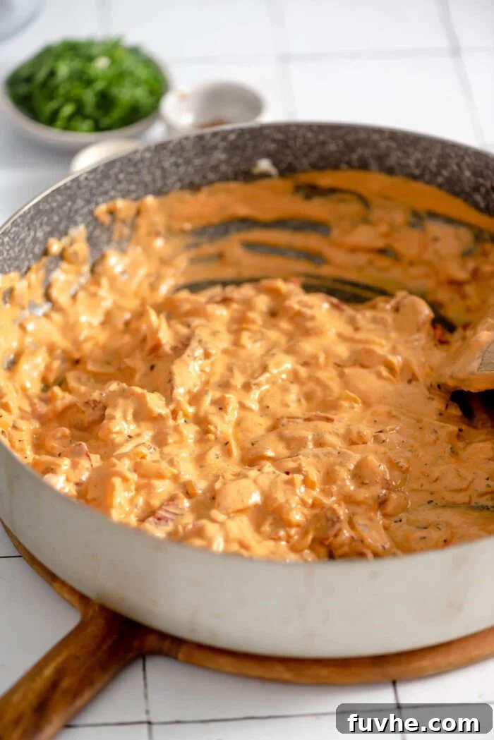 The rich, thick, and creamy sun-dried tomato sauce simmering gently in a large skillet, ready to be combined with pasta.