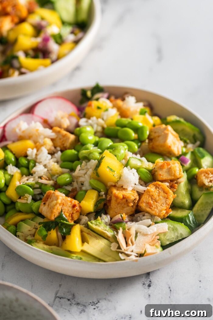 Healthy bowl with rice, avocado, tofu, mango salsa, radish, edamame and cucumber, ready to be enjoyed.