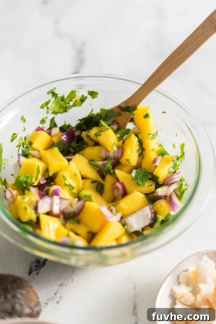 Vibrant mango salsa with red onion, cilantro, and jalapeño, freshly mixed in a small bowl.