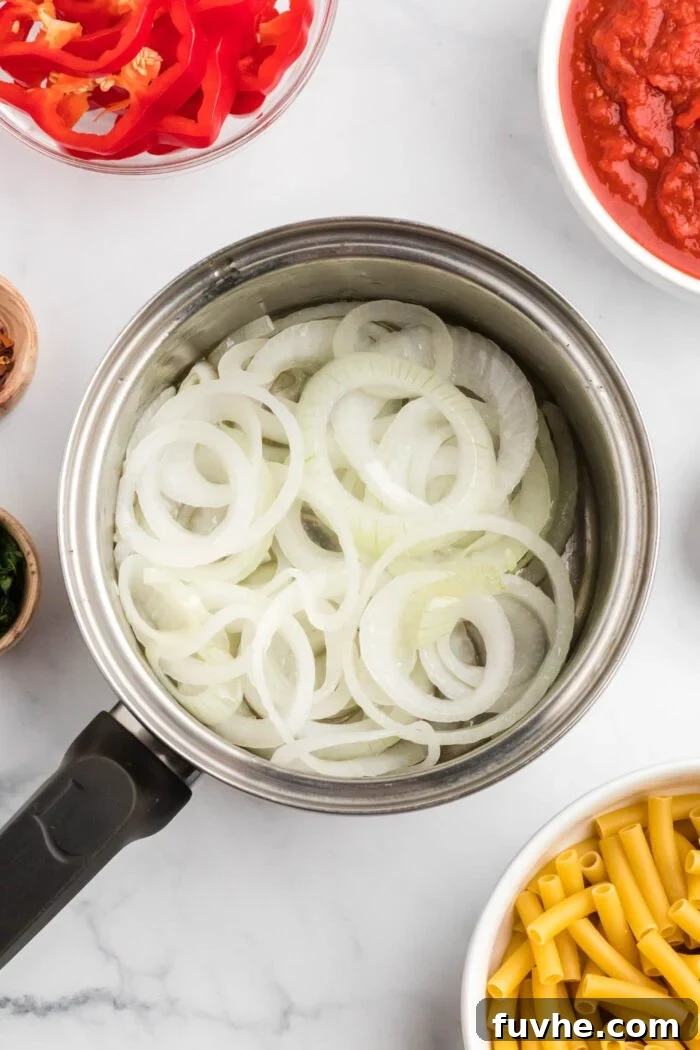 Hearty Plant-Based Baked Ziti 4 Chopped onions cooking in a large sauce pan.
