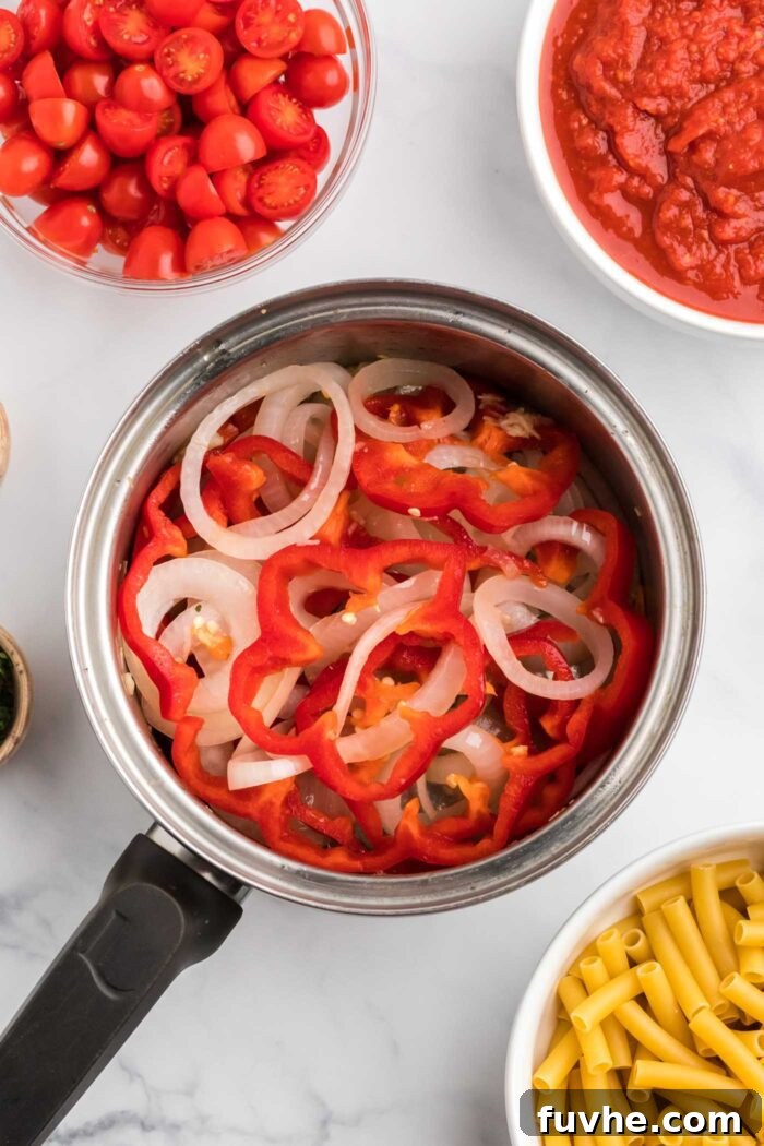 Hearty Plant-Based Baked Ziti 5 Red bell pepper and onion cooking in a large saucepan.