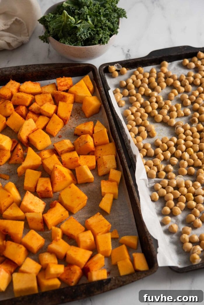 Vibrant Vegan Quinoa Fuel Bowls 4 One baking pan with cubed butternut squash on it beside another with chickpeas on it, both lined with parchment paper, ready for roasting.
