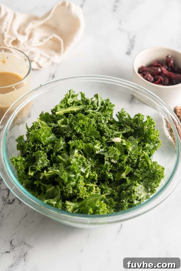 Vibrant Vegan Quinoa Fuel Bowls 6 A large glass bowl filled with chopped kale, glistening with minced garlic and olive oil, in the process of being massaged.