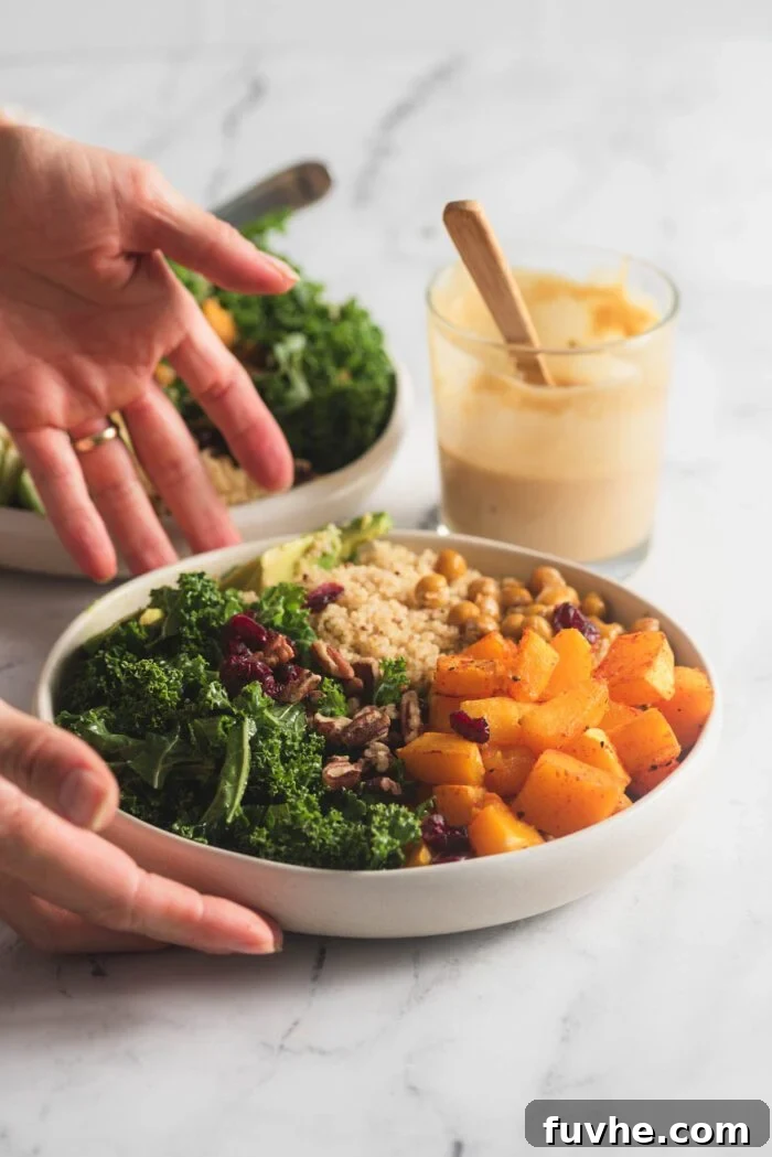 Vibrant Vegan Quinoa Fuel Bowls 7 Hands carefully placing a vibrant quinoa, squash, kale, and cranberry power bowl onto a counter, with a small jar of dressing in the background.