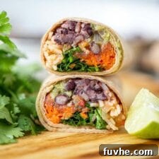 Two halves of a black bean burrito stacked on top of each other on a cutting board.