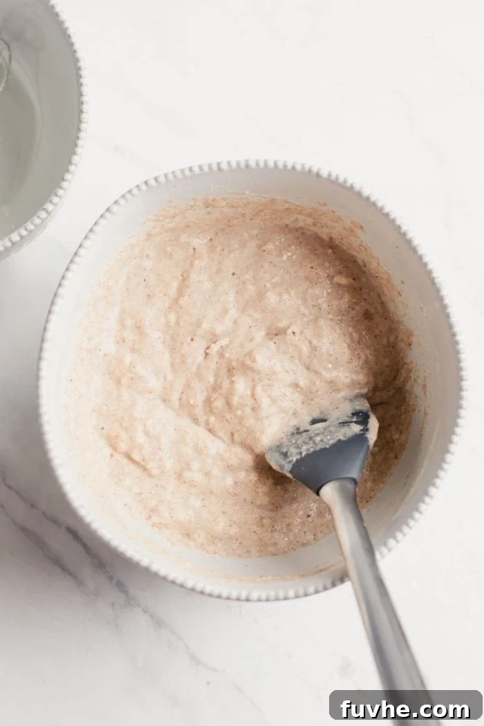 A thick, luscious pancake batter in a white mixing bowl, ready for cooking.