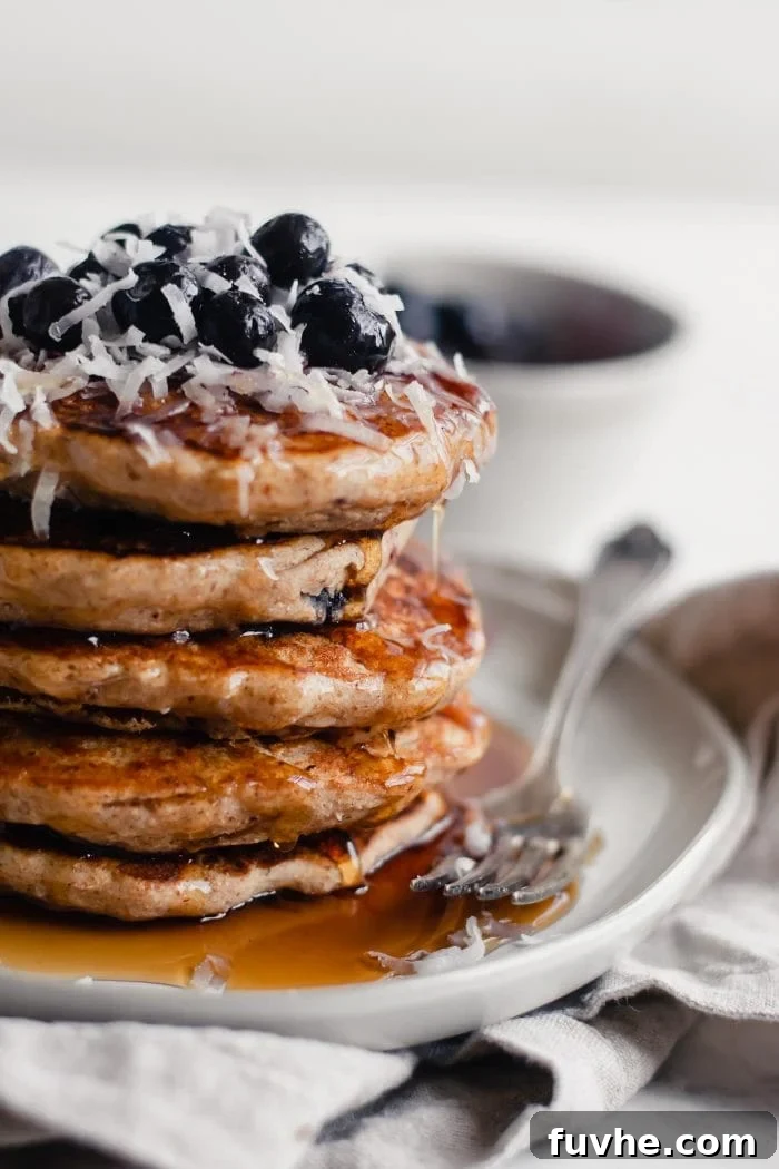 A close-up shot of a stack of fluffy vegan blueberry pancakes, with rich maple syrup cascading down the sides.