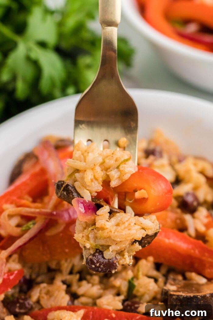 Zesty Plant-Powered Fajita Bowls 11 Fork full of rice, beans and bell peppers held over a vegetarian fajita bowl.