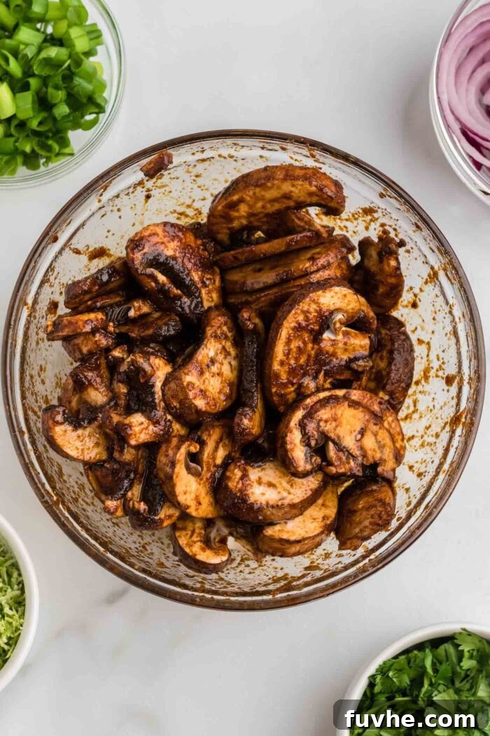 Zesty Plant-Powered Fajita Bowls 5 Sliced mushrooms marinated in fajita spices, soy sauce and balsamic vinegar in a glass bowl.