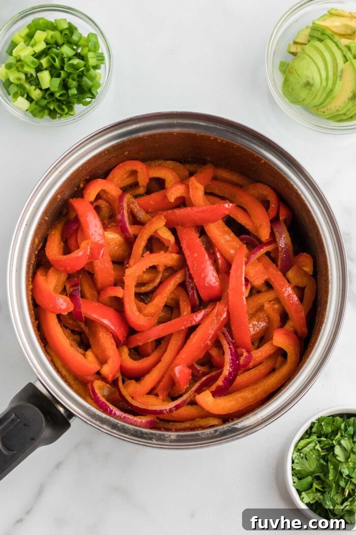 Zesty Plant-Powered Fajita Bowls 7 Sliced bell peppers and onions cooking in a large pan.