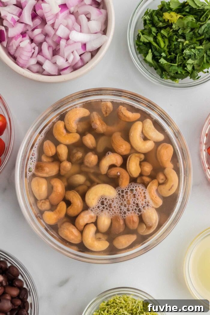 Chipotle Lime Vegan Pasta Salad 4 Roasted cashews soaking in a bowl of water. Beside the cashews there are more bowls with cilantro, red onion, black bowls and lime zest.