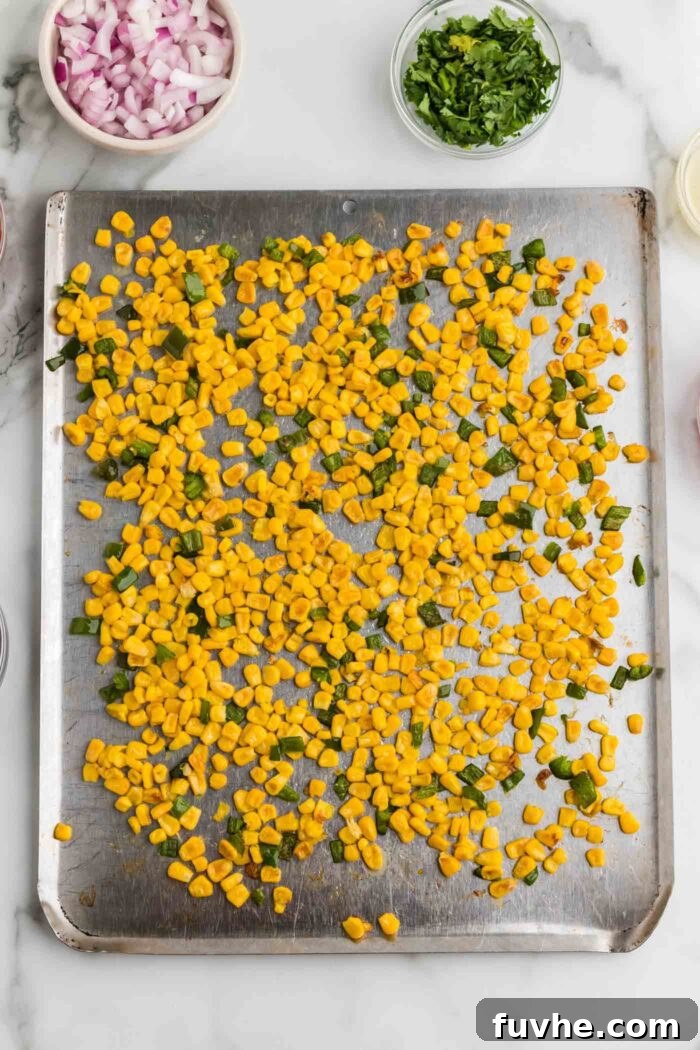 Chipotle Lime Vegan Pasta Salad 6 Roasted corn kernels and diced jalapeno on a baking tray.