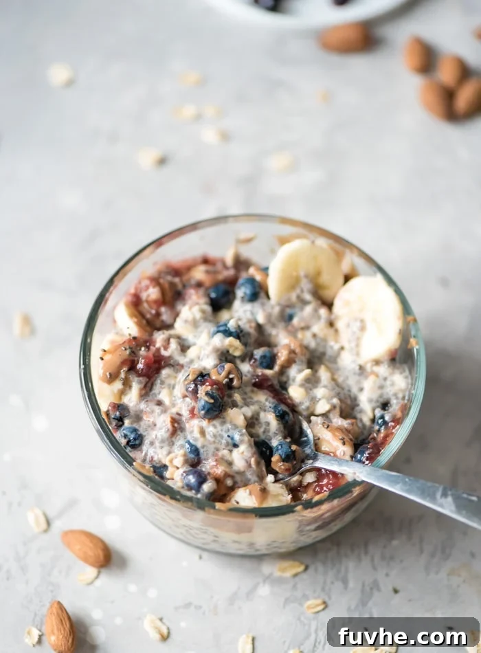 Overnight Banana Bliss 6 A beautifully composed bowl of overnight chia seed oatmeal, artfully topped with golden almonds, plump blueberries, a rich dollop of jam, and gracefully sliced banana, showcasing a perfect, ready-to-eat breakfast.
