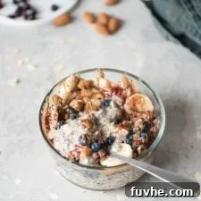 Overnight Banana Bliss 7 A delicious bowl of blueberry and banana chia seed oatmeal topped with nuts and sliced banana. A spoon is ready for tasting.