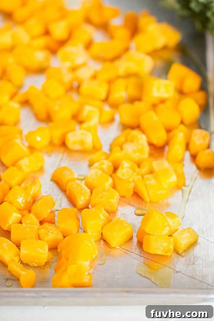 Golden-brown, perfectly roasted butternut squash cubes spread out on a baking tray, ready to be added to the salad.
