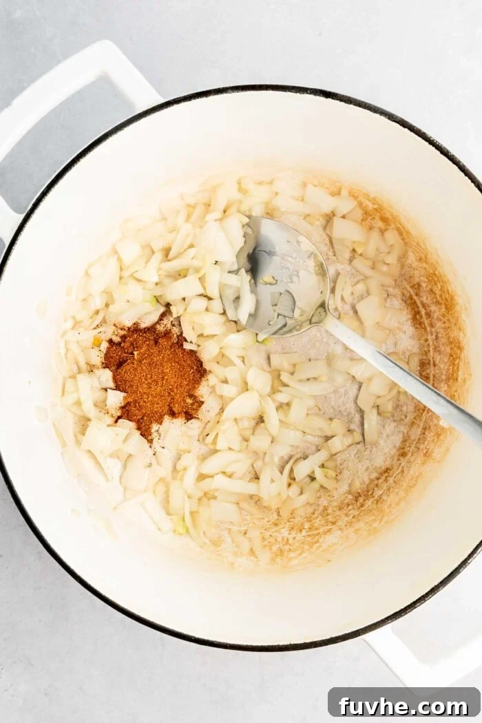 Sunny Vegan Corn Chowder 4 Garlic, diced onion, and aromatic Cajun seasoning gently cooking in a large soup pot, their fragrances filling the air as they form the flavorful base of the chowder.