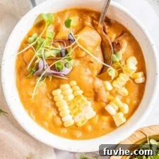 Sunny Vegan Corn Chowder 9 Overhead view of a handled bowl of creamy vegan summer corn chowder soup topped with fresh microgreens and corn kernels.