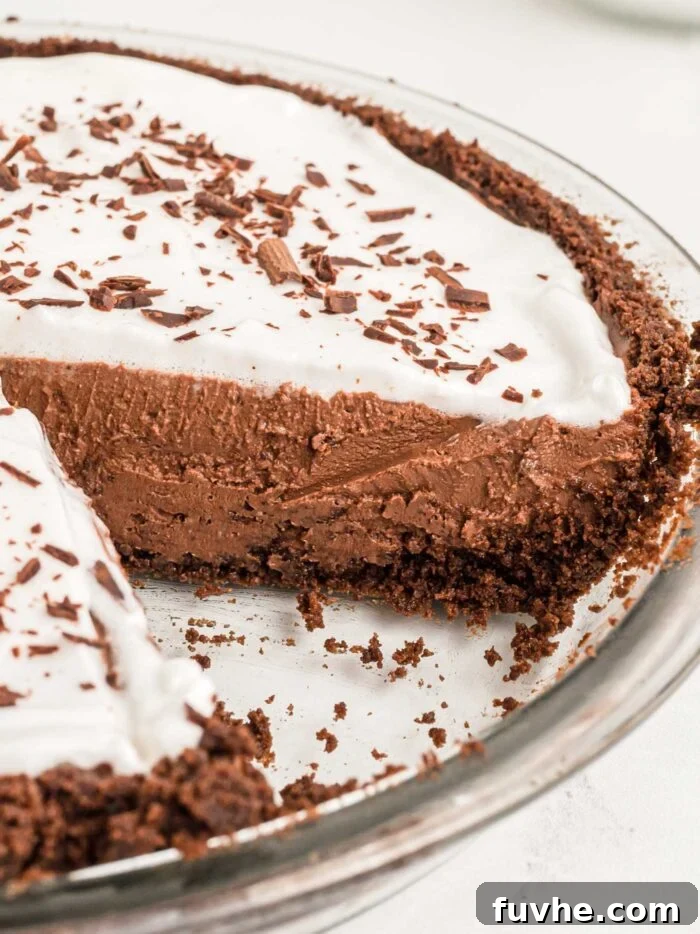 A close-up view of the no-bake vegan chocolate pie in its dish, with one slice removed to reveal the smooth, firm, and inviting texture of the chocolate filling.