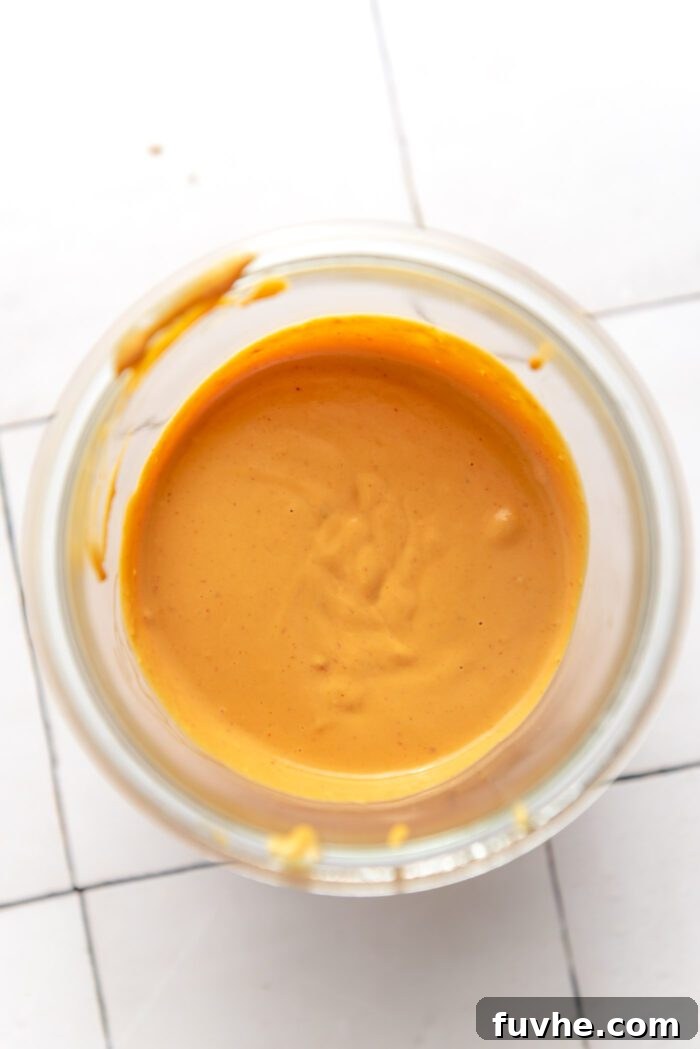 Spiced Sweet Potato and Black Bean Tacos 7 A charming Weck jar filled with smooth, creamy chipotle queso sauce, positioned on a stylish checkered countertop, inviting a drizzle.