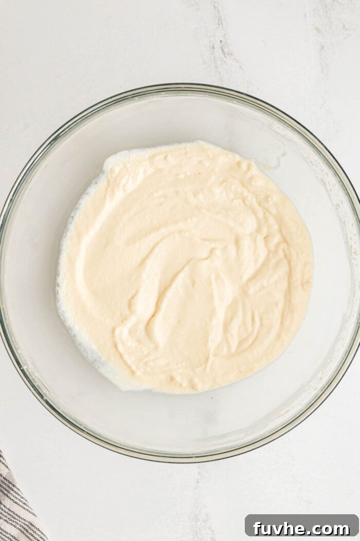 Decadent Vegan Tiramisu 13 Tofu and powdered sugar blended into a creamy mixture in a glass mixing bowl.
