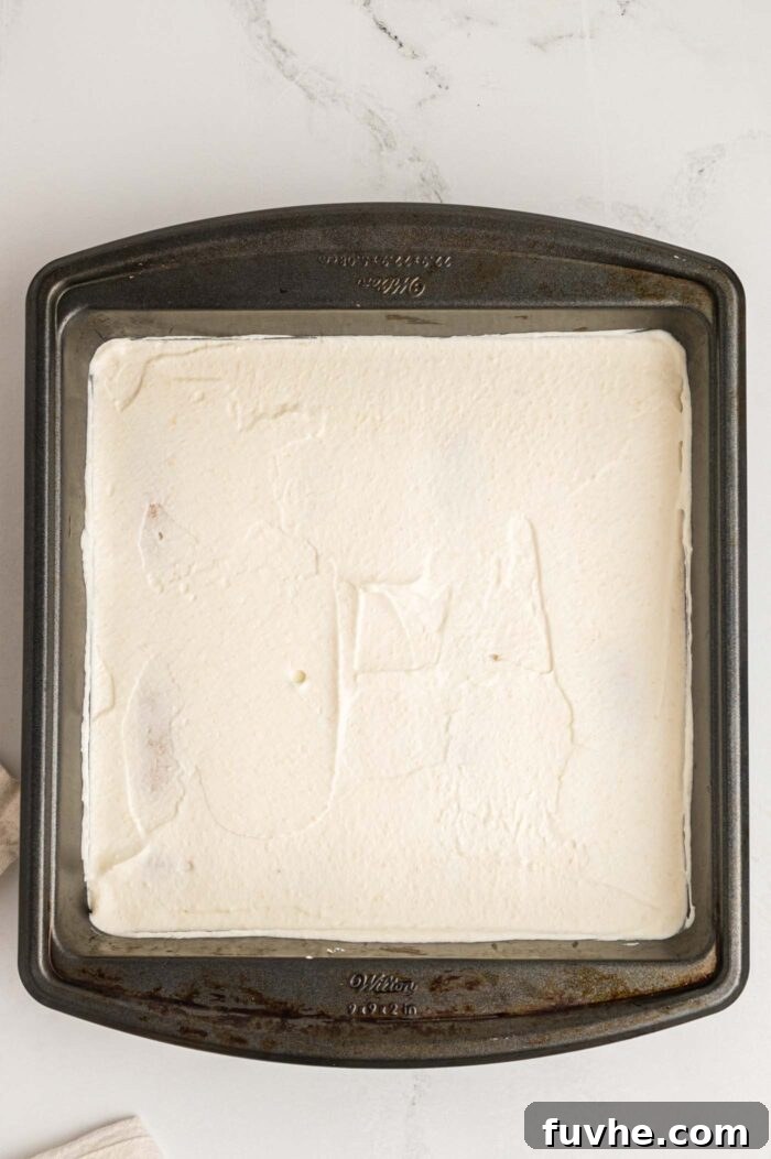 Decadent Vegan Tiramisu 17 Marscapone cream cheese spread in an even layer in a square baking pan.