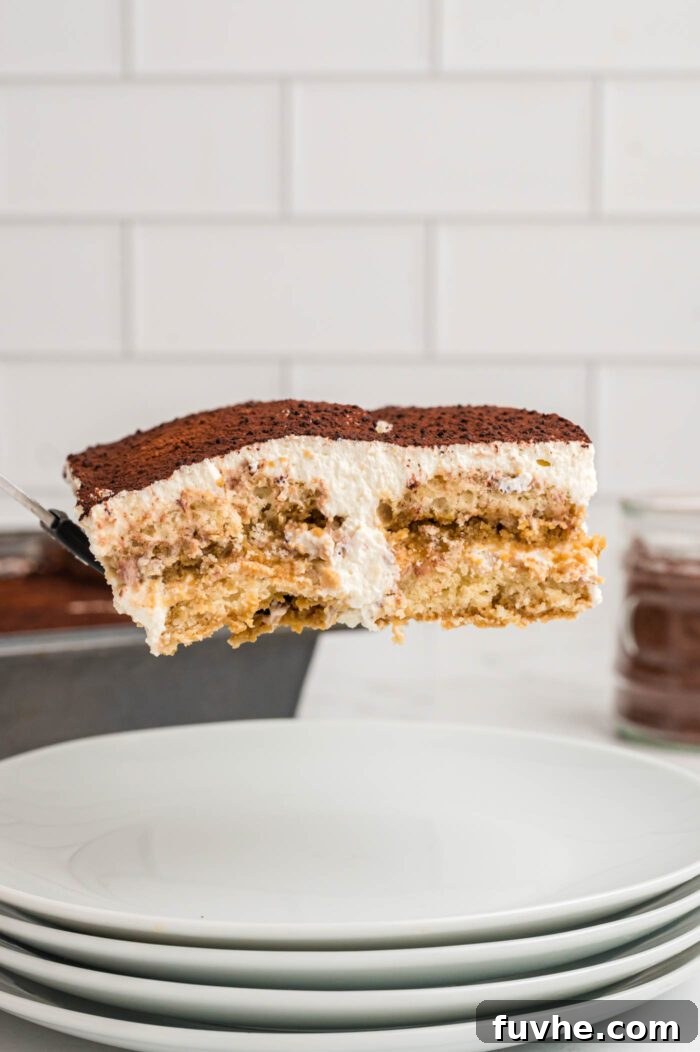 Decadent Vegan Tiramisu 22 A square of tiramisu on a spatula being transferred from a pan to a small serving plate.
