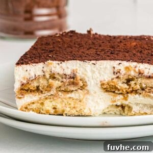 Decadent Vegan Tiramisu 23 Square of tiramisu cake on a plate. You can see the layers of ladyfingers, cream filling and cocoa powder on top.