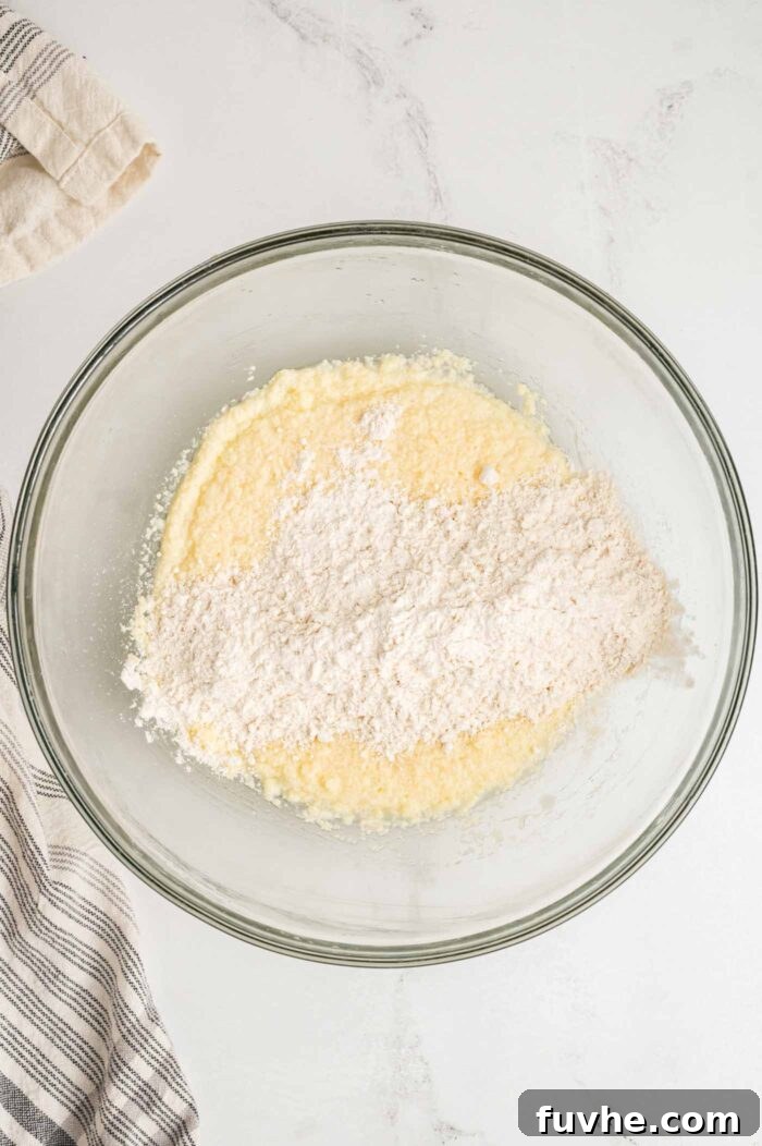 Decadent Vegan Tiramisu 8 A creamed butter and sugar mixture in a glass mixing bowl with some flour added on top of it, ready to be mixed together.
