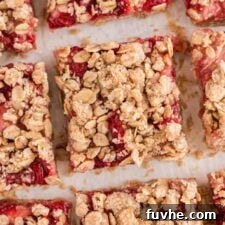 An overhead close up of a number of strawberry oat bars with an oatmeal crumble topping.
