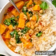 Overhead view into a bowl of creamy butternut squash curry with chickpeas and spinach served with rice.