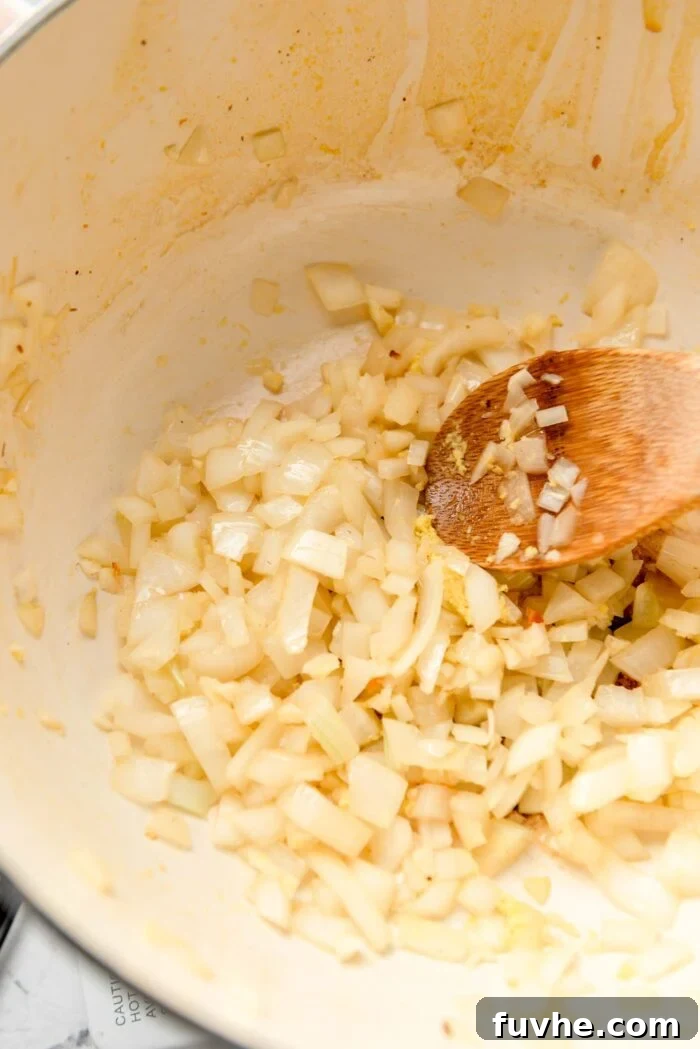 Finely chopped onion, minced garlic, and grated ginger gently sautéing in a large pot, releasing their aromatic flavors.