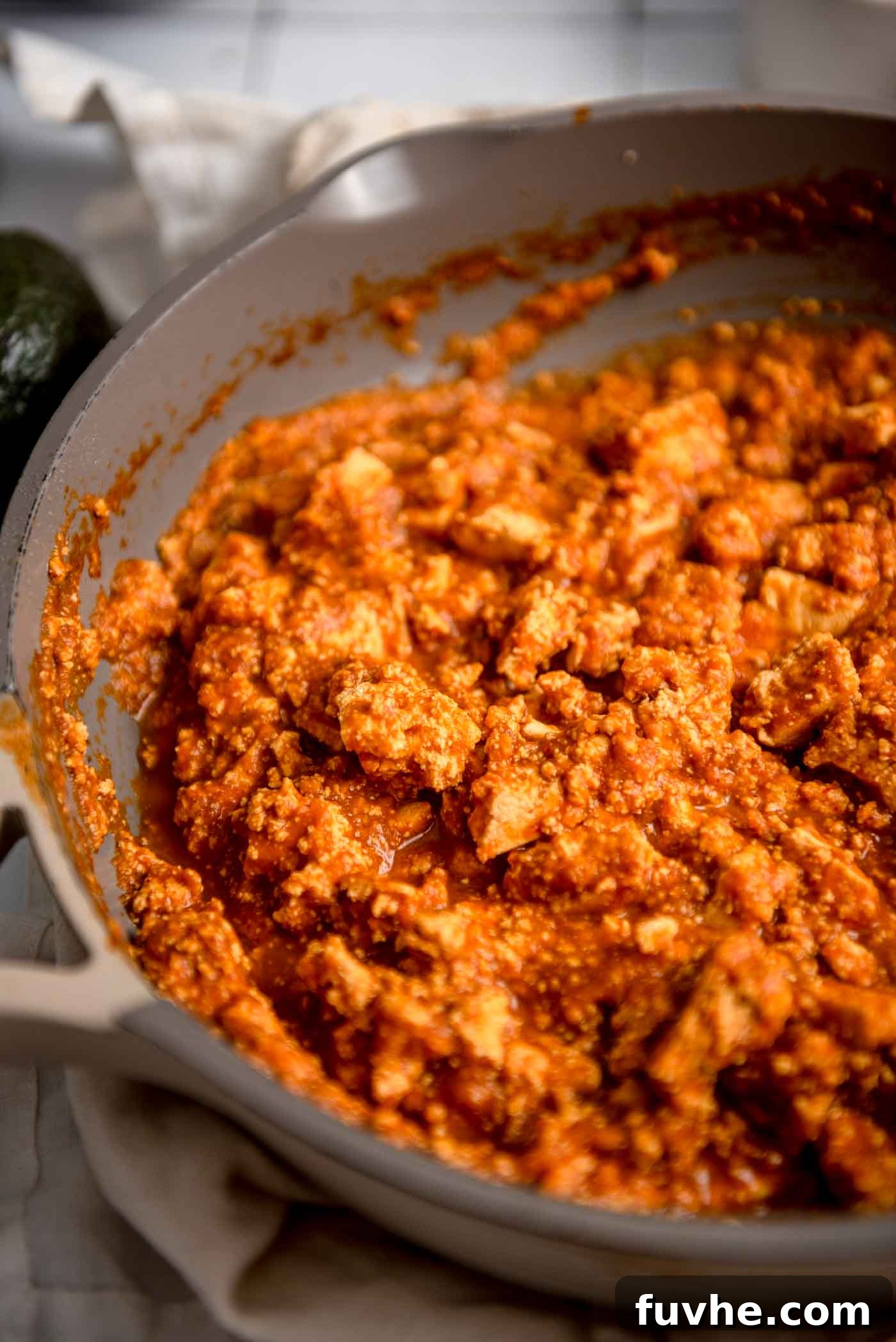 A copycat recipe of spicy tofu sofritas which is crumbled tofu in sauce cooking in a skillet, ready to be served in a burrito bowl.