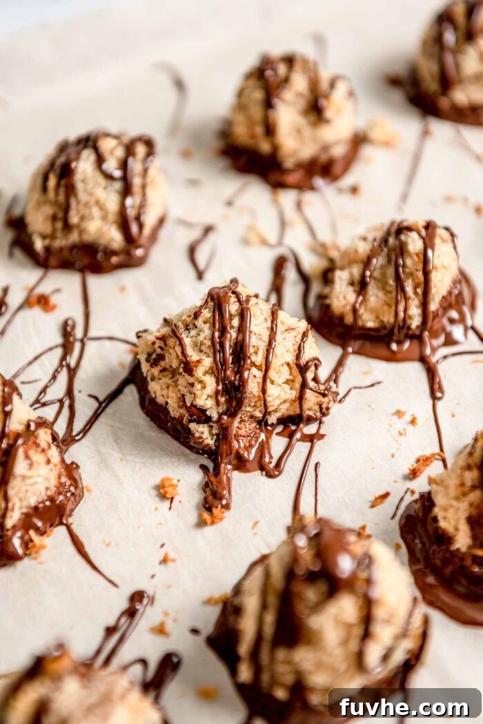 Plant-Powered Almond Coconut Dreams 9 Almond macaroons drizzled with melted chocolate on a baking tray lined with parchment paper.