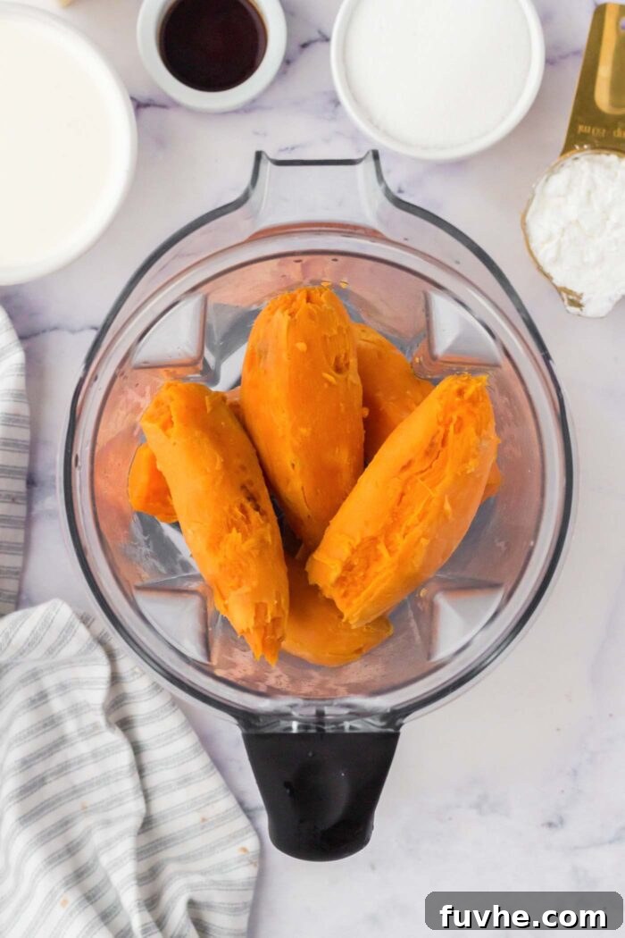 Whole baked and peeled sweet potatoes in a blende container.