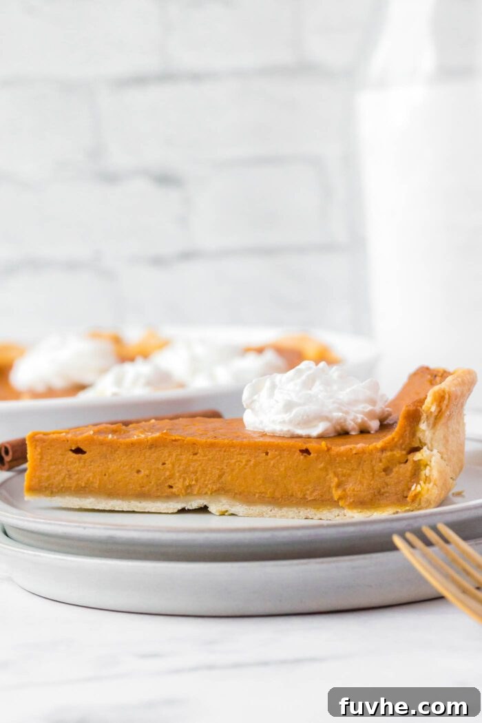 A slice of sweet potato pie topped with a dollop of whipped cream on a plate.