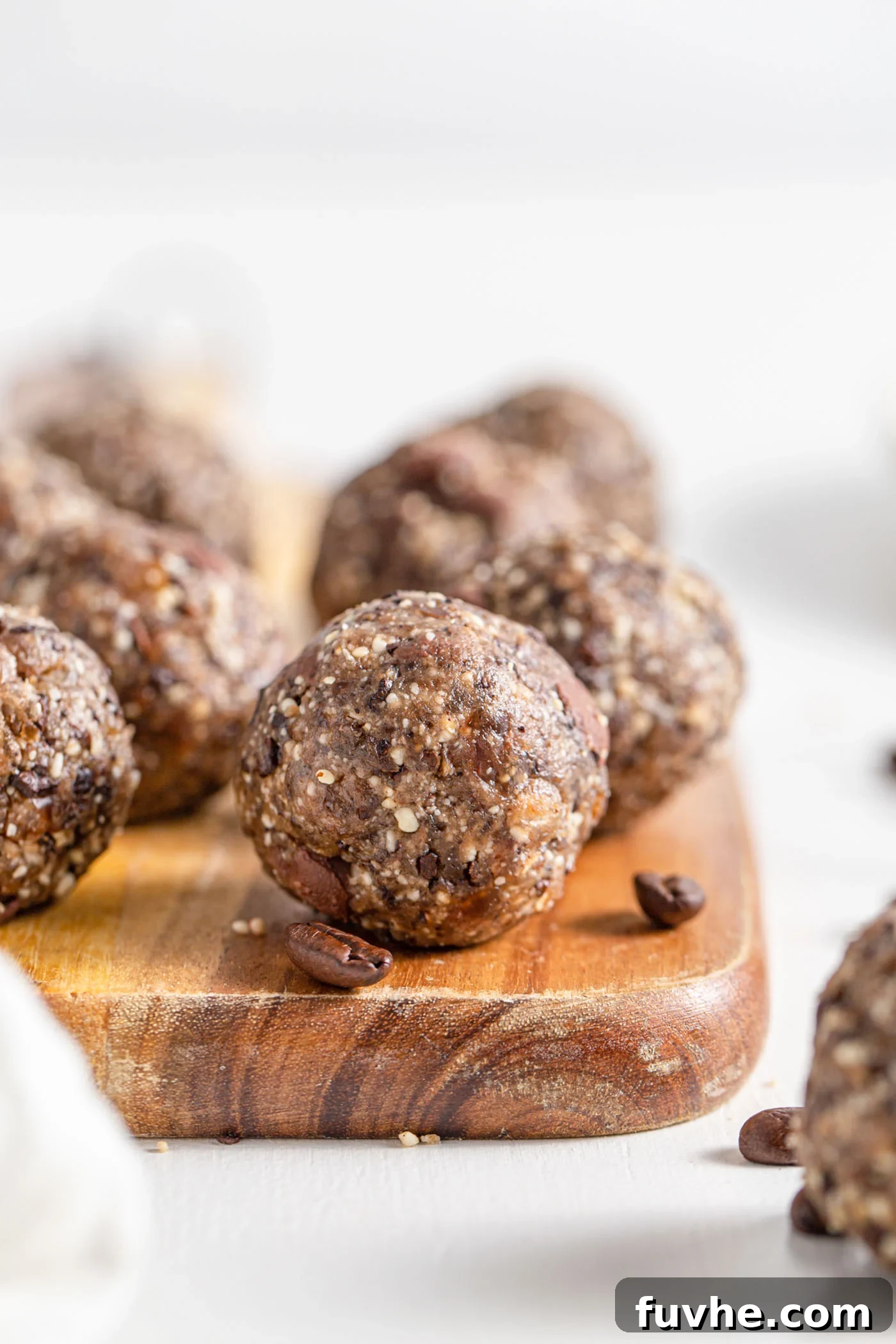 A chocolate chip energy ball on a cutting board. More balls in background.
