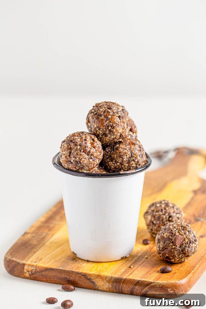 Small cup filled with chocolate energy balls sitting on a cutting board.