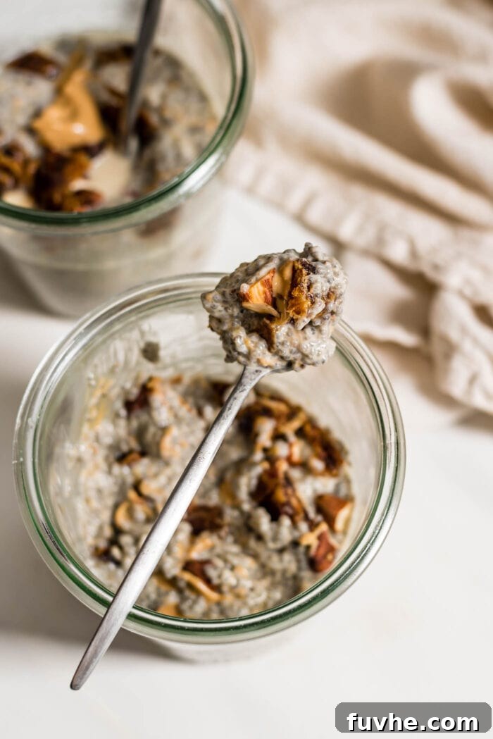A small spoon, laden with a spoonful of creamy chia pudding, rests elegantly on the rim of a clear jar filled with the prepared chia pudding, ready to be enjoyed.