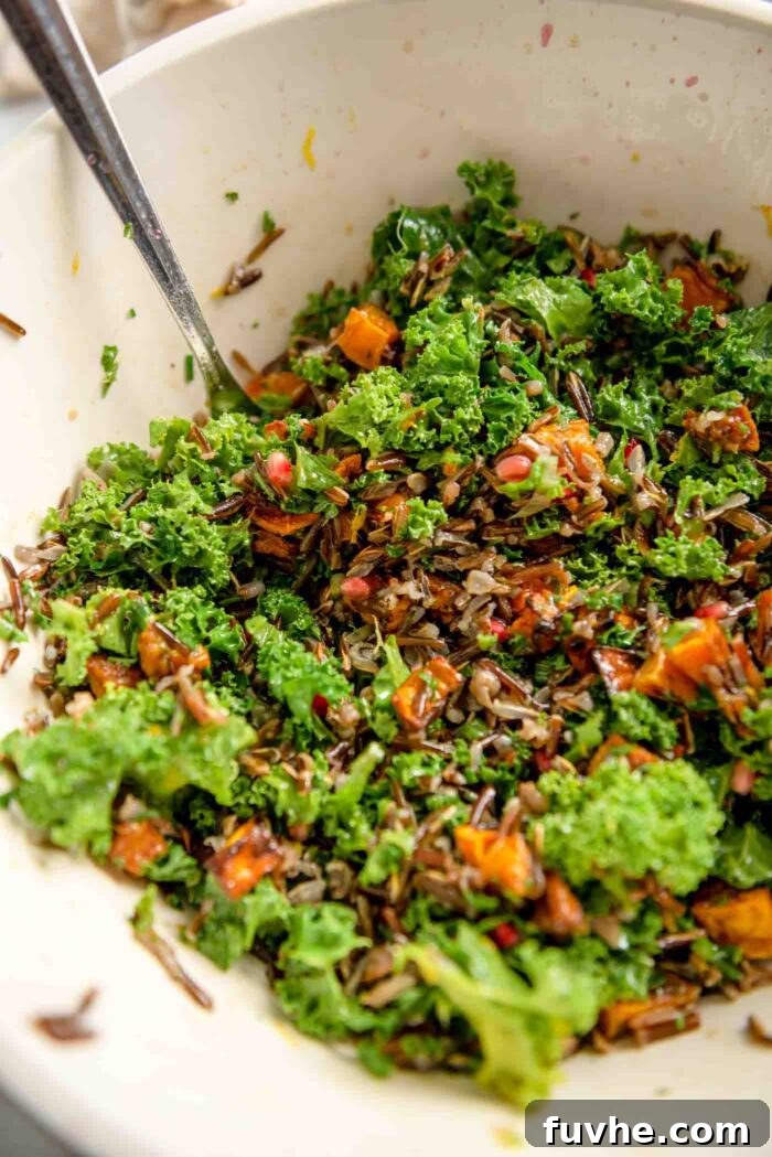 Rustic Wild Rice Salad 7 A wild rice, kale and squash salad mixed in a large mixing bowl, showing all ingredients coated in dressing.
